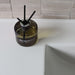 Overhead view of the Fireball luxury fragrance diffuser with three reed sticks beside a bathroom sink.
