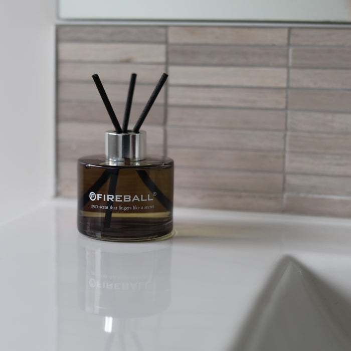 Fireball luxury fragrance diffuser with reed sticks displayed beside a bathroom sink for use in the home.