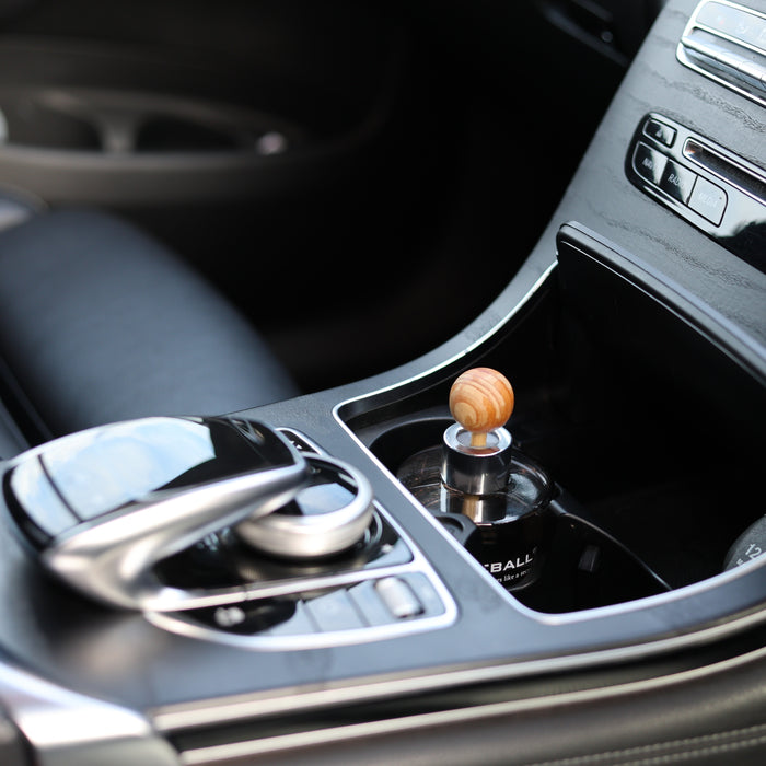 Fireball premium car fragrance diffuser installed in the centre cup holder of a Mercedes-Benz GLC viewed from the driver's seat.