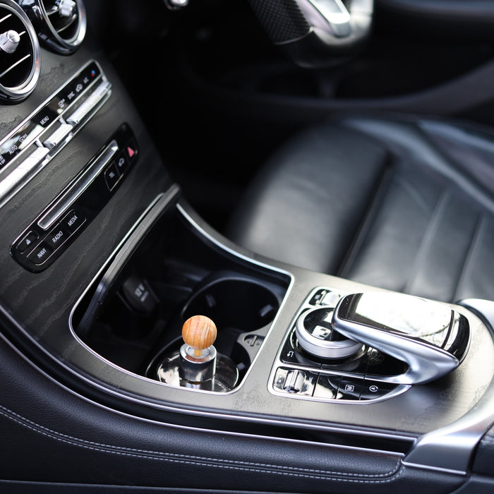 Fireball luxury car fragrance diffuser sitting in the centre cup holder of a Mercedes-Benz GLC viewed from the passenger side.